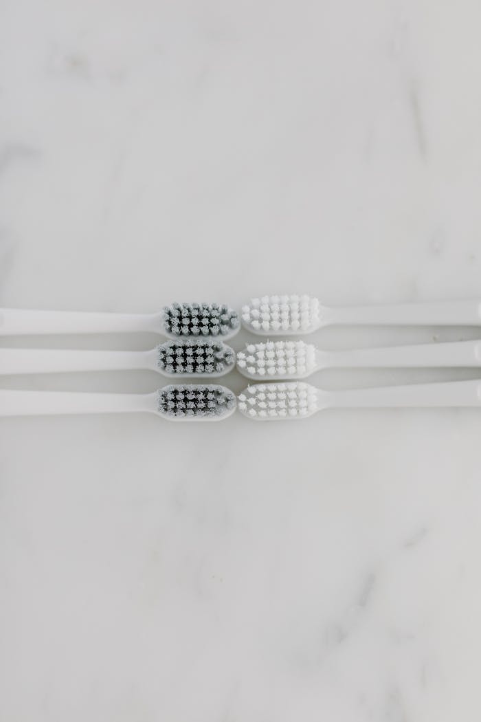 A simple and clean top view of two white toothbrushes on a marble surface, showcasing hygiene in a minimalist style.